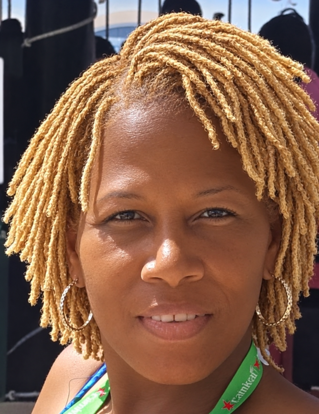 Close-up portrait of a smiling client with chin-length honey-blonde Sister Locs styled in a rounded, face-framing bob